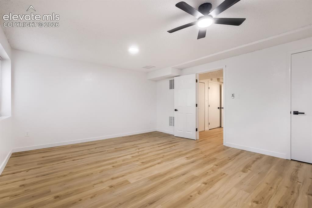 Image 18 of 25: Neutral interior space featuring wood-finish flooring, a ceiling fan with i