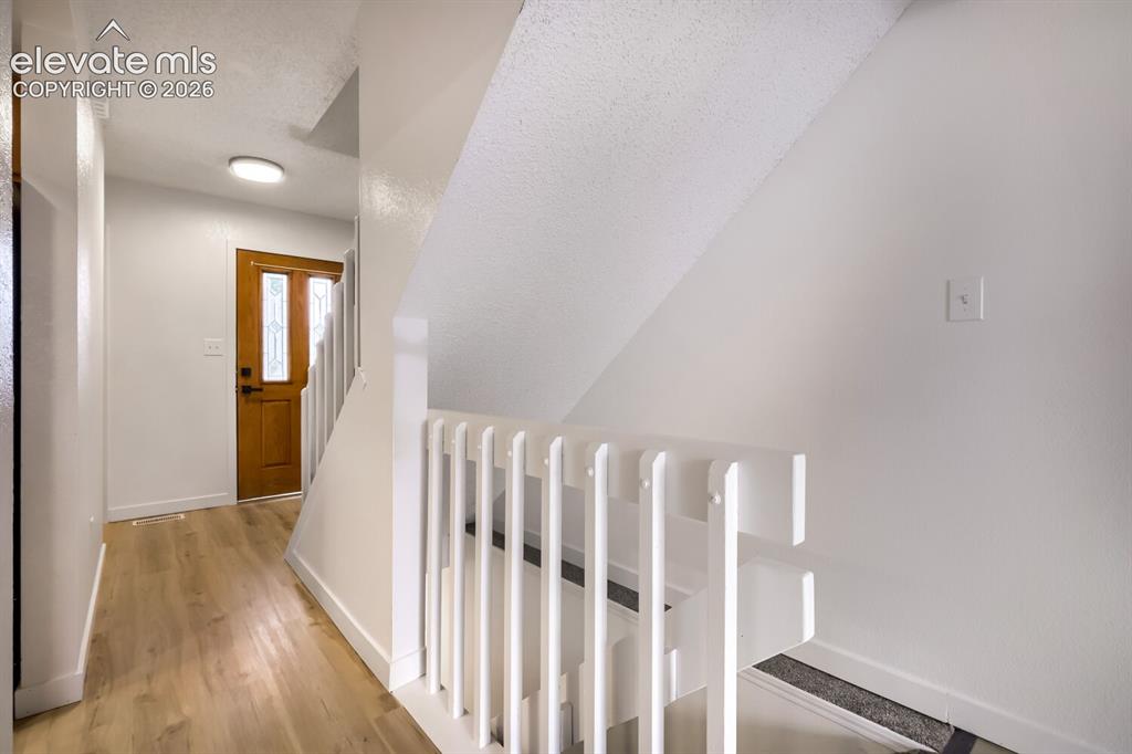 Image 2 of 25: Wood-finish flooring, white staircase railing, and entry door featuring dec
