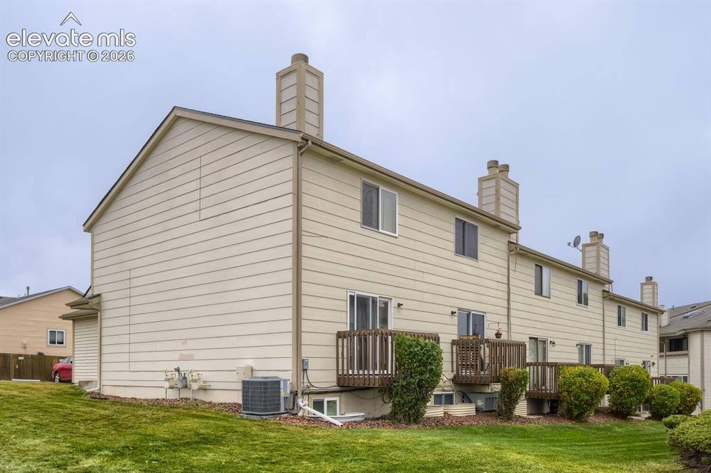 Image 21 of 25: Exterior elevation featuring beige horizontal siding, multiple chimneys, ra