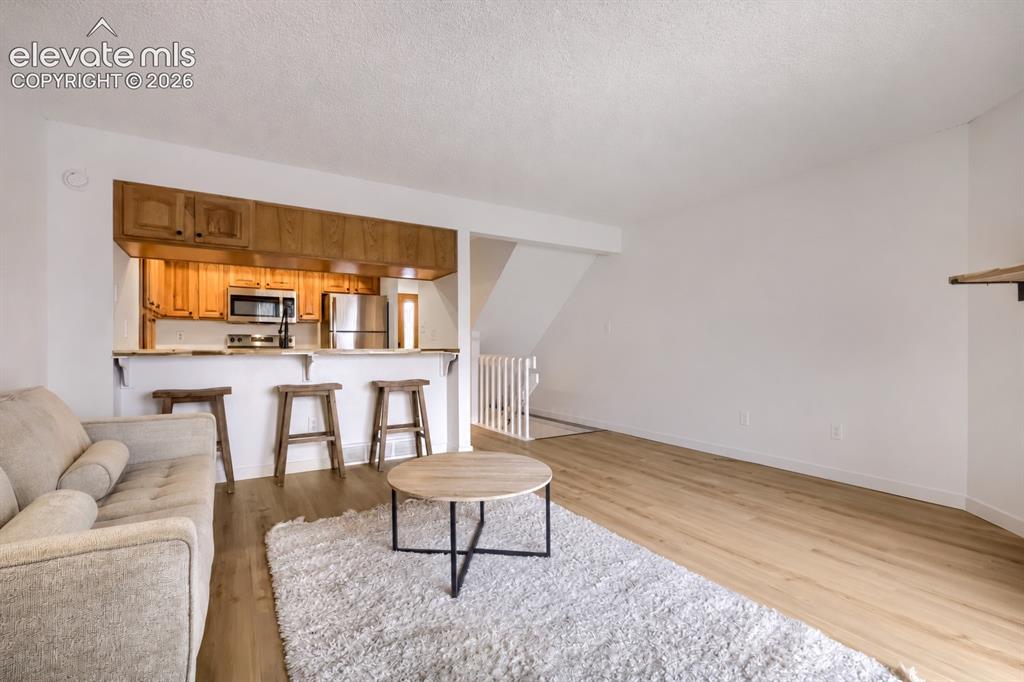 Image 4 of 25: Open-concept interior featuring wood-finish flooring, kitchen with overhead
