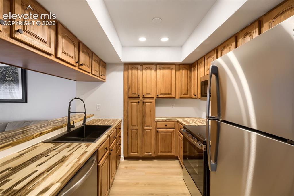 Image 8 of 25: Kitchen featuring wood cabinetry, butcher block countertops, stainless stee