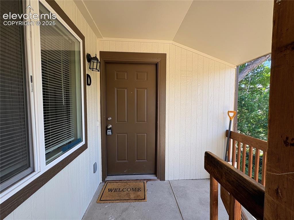 Image 2 of 11: Covered entry patio with vertical siding, a paneled entry door, and a singl