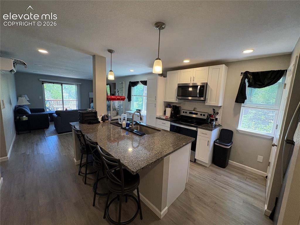 Image 3 of 11: Modern kitchen featuring white cabinetry, stainless steel appliances, a gra