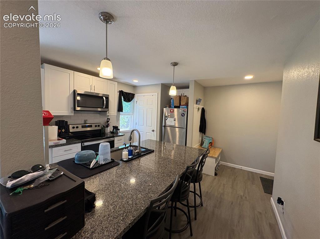 Image 4 of 11: Kitchen featuring an expansive granite-finish island with seating, pendant