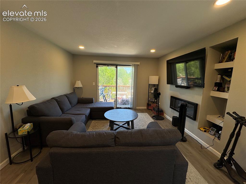 Image 9 of 11: Living area featuring wood-finish flooring, recessed lighting, and a built-