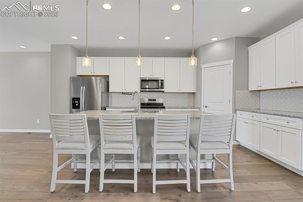 Image 11 of 40: Kitchen featuring appliances with stainless steel finishes, white cabinets,