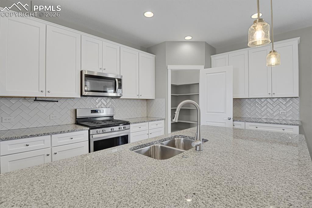 Image 14 of 40: Kitchen featuring stainless steel appliances, light stone countertops, whit