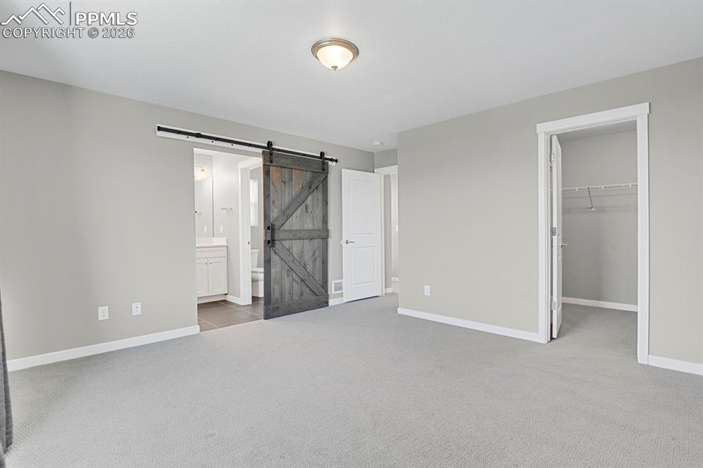 Image 19 of 40: Primary bedroom and barn door leading into en suite bathroom