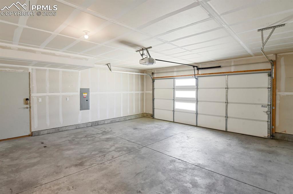 Image 31 of 40: Garage with electric panel and a My Q garage door opener and service door.