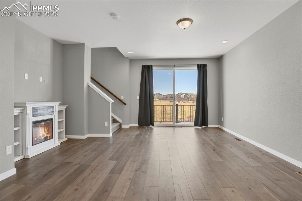 Image 7 of 40: Unfurnished living room with a glass covered fireplace, wood finished floor