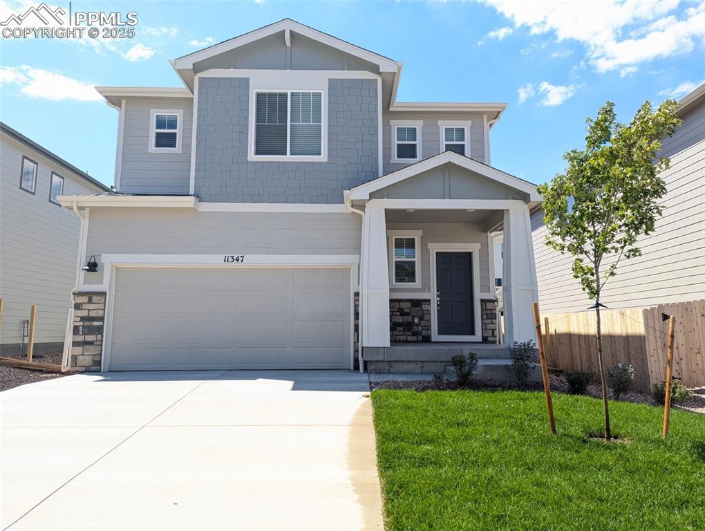 Caption: Craftsman-style house with stone siding, a garage, driveway, and covered porch