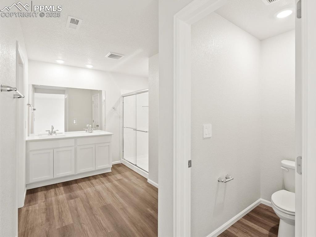 Image 13 of 23: Bathroom featuring wood finished floors, a shower stall, recessed lighting,