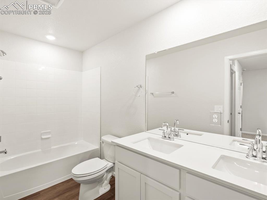 Image 19 of 23: Bathroom featuring double vanity, wood finished floors, and shower / tub co