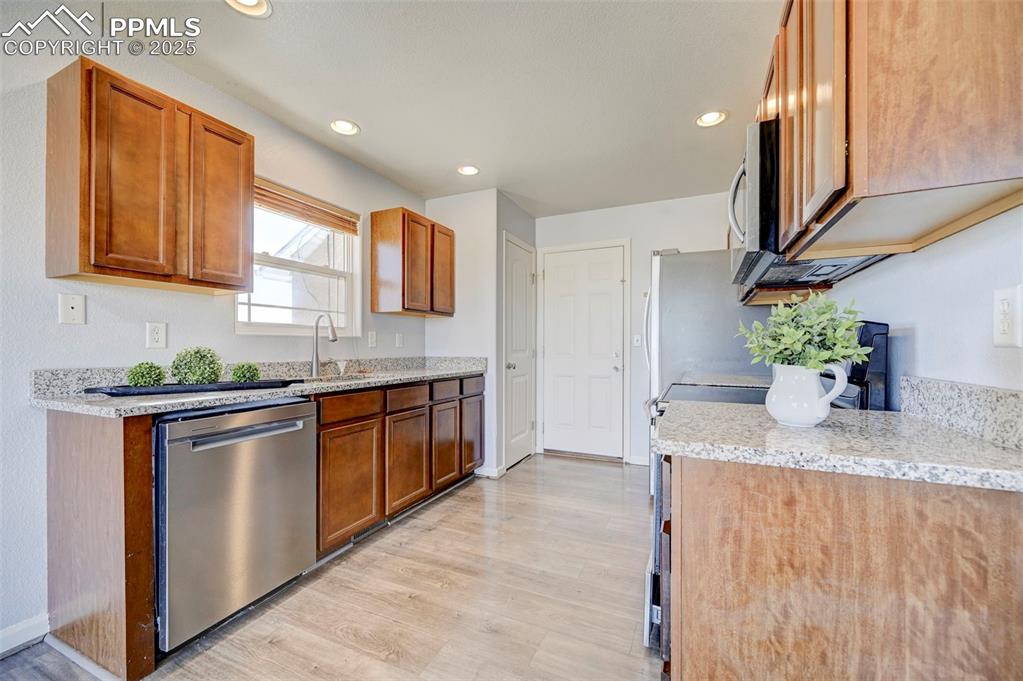 Image 11 of 37: Kitchen with light wood-style flooring, recessed lighting, a sink, stainles
