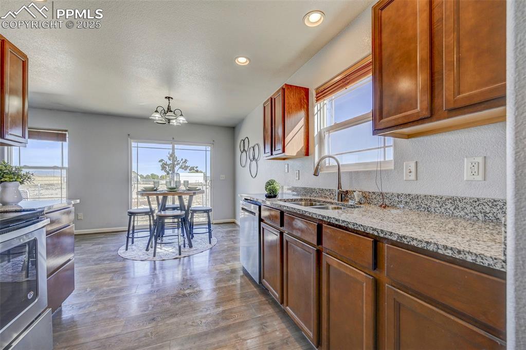 Image 12 of 37: Kitchen featuring light stone countertops, a chandelier, dark wood finished