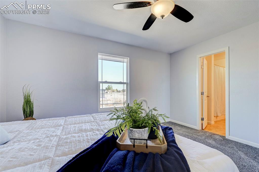 Image 17 of 37: Carpeted bedroom featuring ensuite bath, a ceiling fan, and baseboards