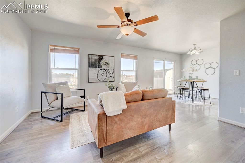Image 4 of 37: Living room with ceiling fan with notable chandelier, wood finished floors,