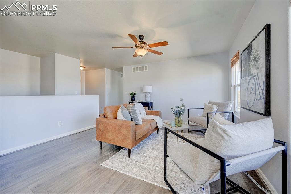 Image 5 of 37: Living area featuring visible vents, baseboards, ceiling fan, and wood fini