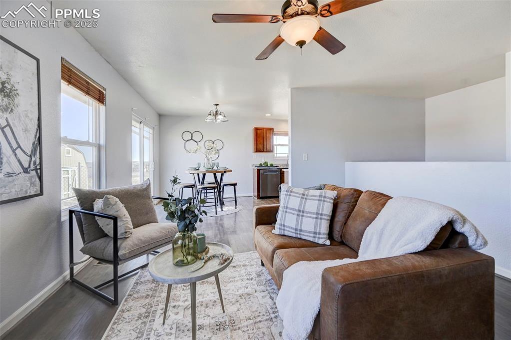 Image 7 of 37: Living area with dark wood-type flooring, ceiling fan with notable chandeli