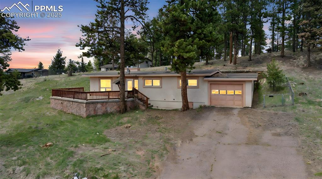Image 21 of 22: View of front facade featuring stucco siding, a garage, dirt driveway, and