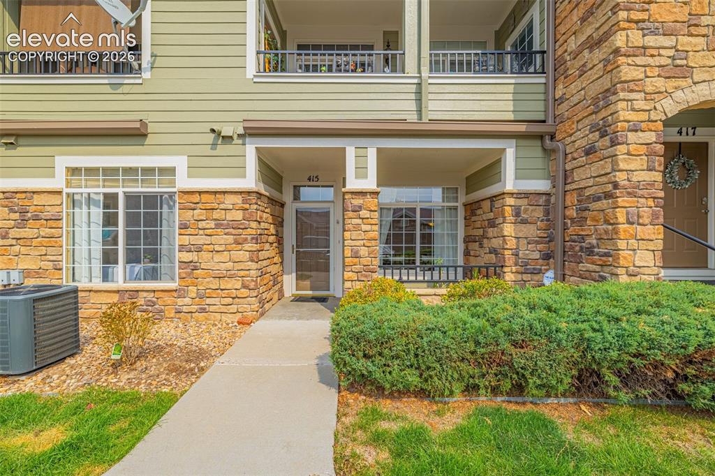 Image 1 of 27: Stone and siding exterior with a covered entry, ground-level windows, and a