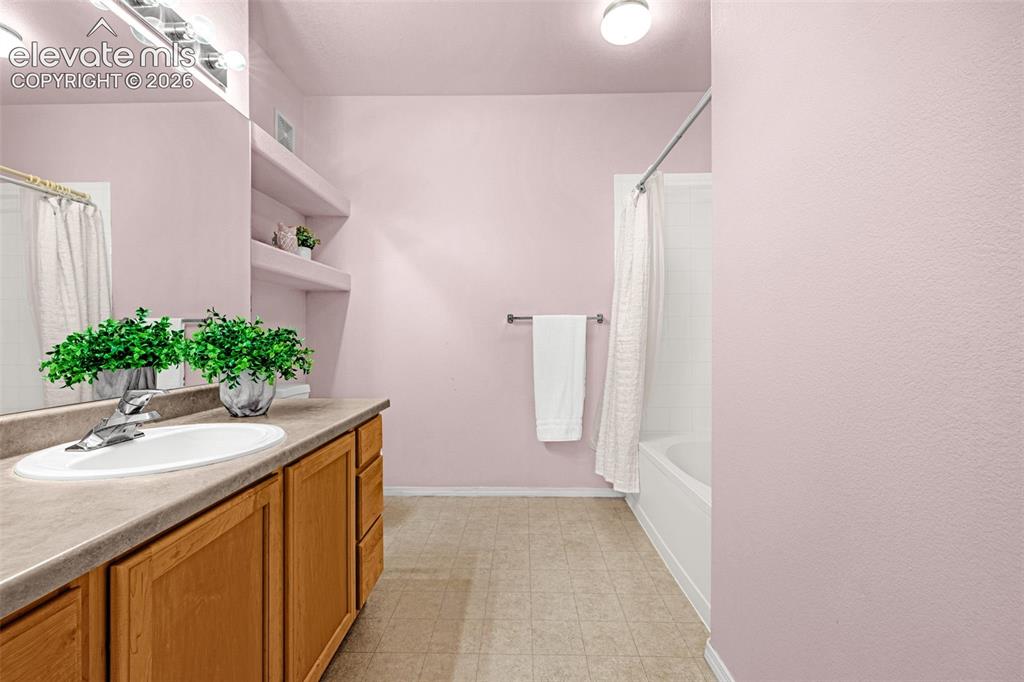 Image 10 of 27: Built-in vanity with a single basin sink, wood-finish cabinetry, and a full