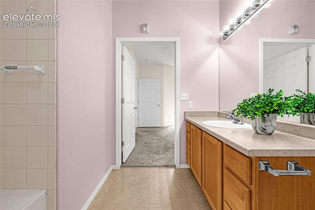 Image 12 of 27: Tile flooring, wood-finish vanity with integrated sink, expansive vanity mi