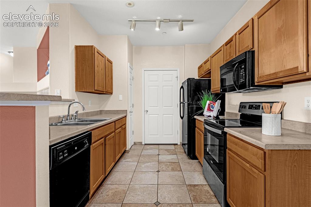 Image 15 of 27: Kitchen featuring wood cabinetry, laminate countertops, a double basin sink