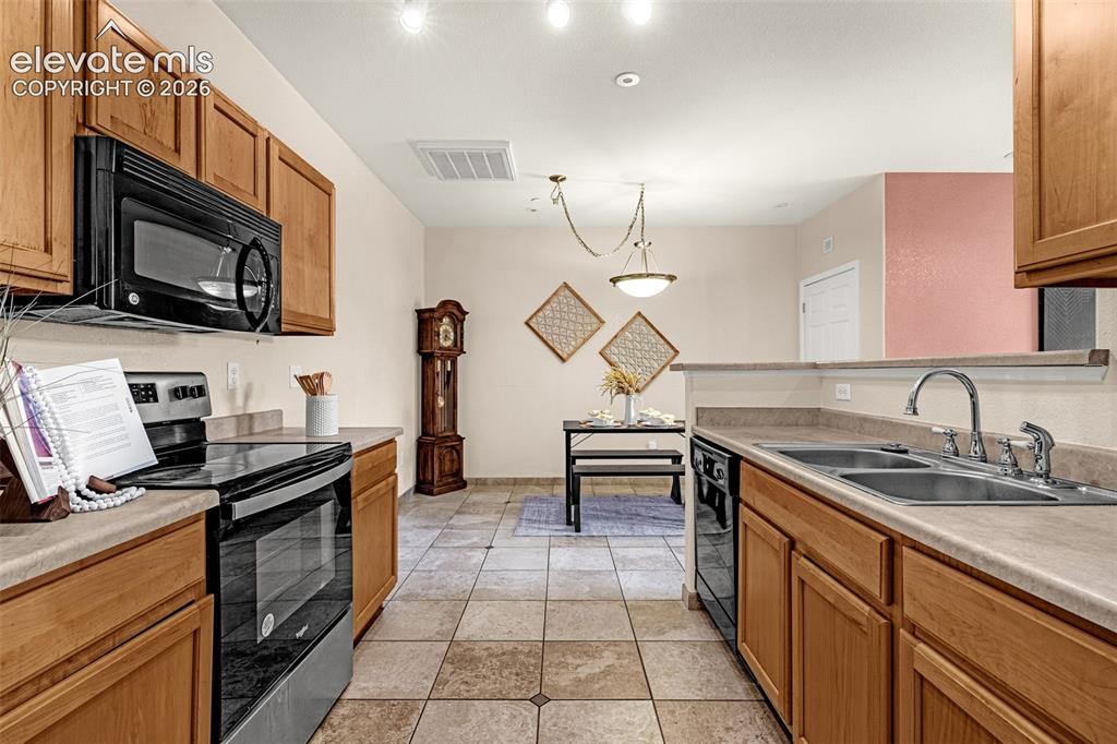 Image 16 of 27: Kitchen featuring wood cabinetry, stainless steel appliances, a double basi