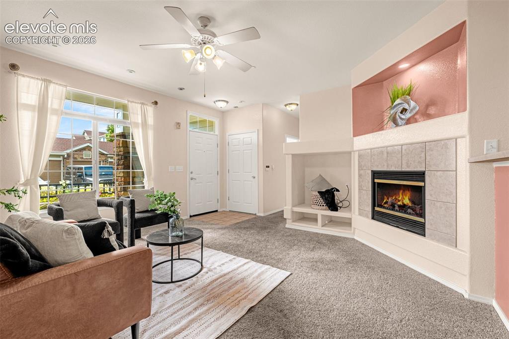 Image 2 of 27: Living area featuring a gas fireplace with a tiled surround, recessed shelv