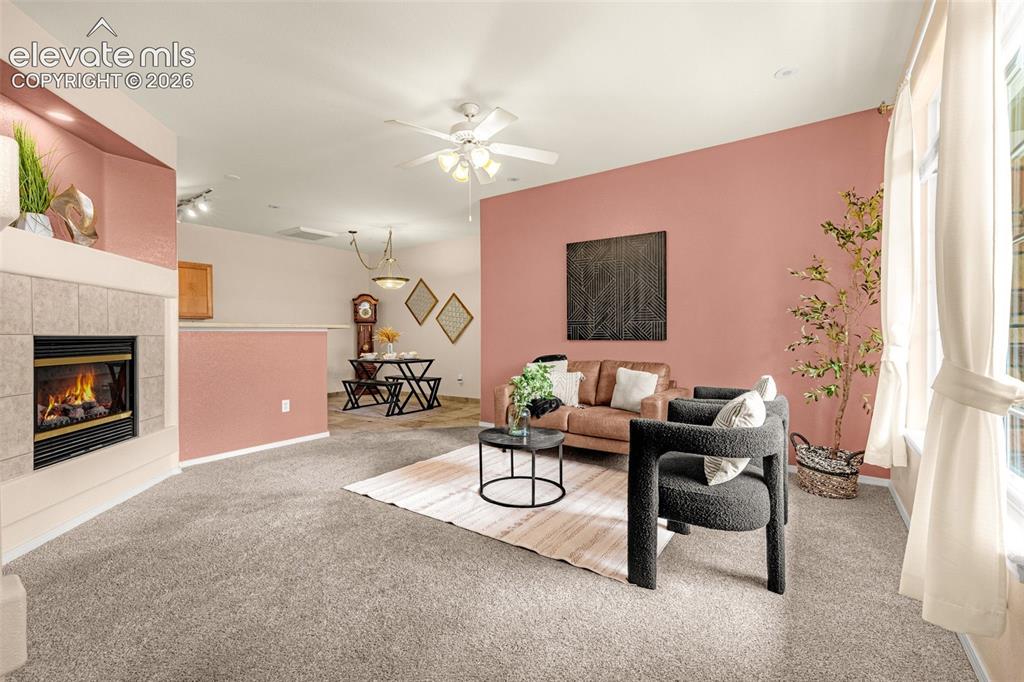 Image 3 of 27: Living area featuring a fireplace with a tile surround, a ceiling fan, and