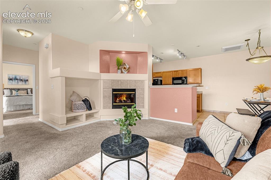 Image 5 of 27: Spacious living area featuring a built-in fireplace with stone-tile surroun