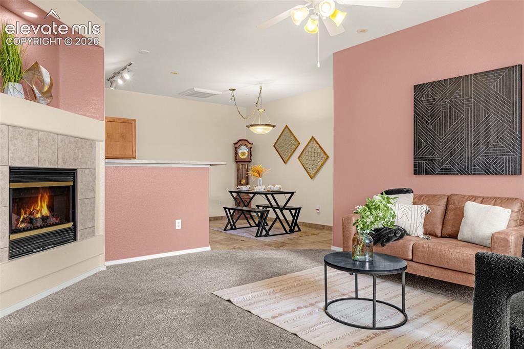 Image 6 of 27: Carpeted living area with a built-in fireplace featuring a tile surround an