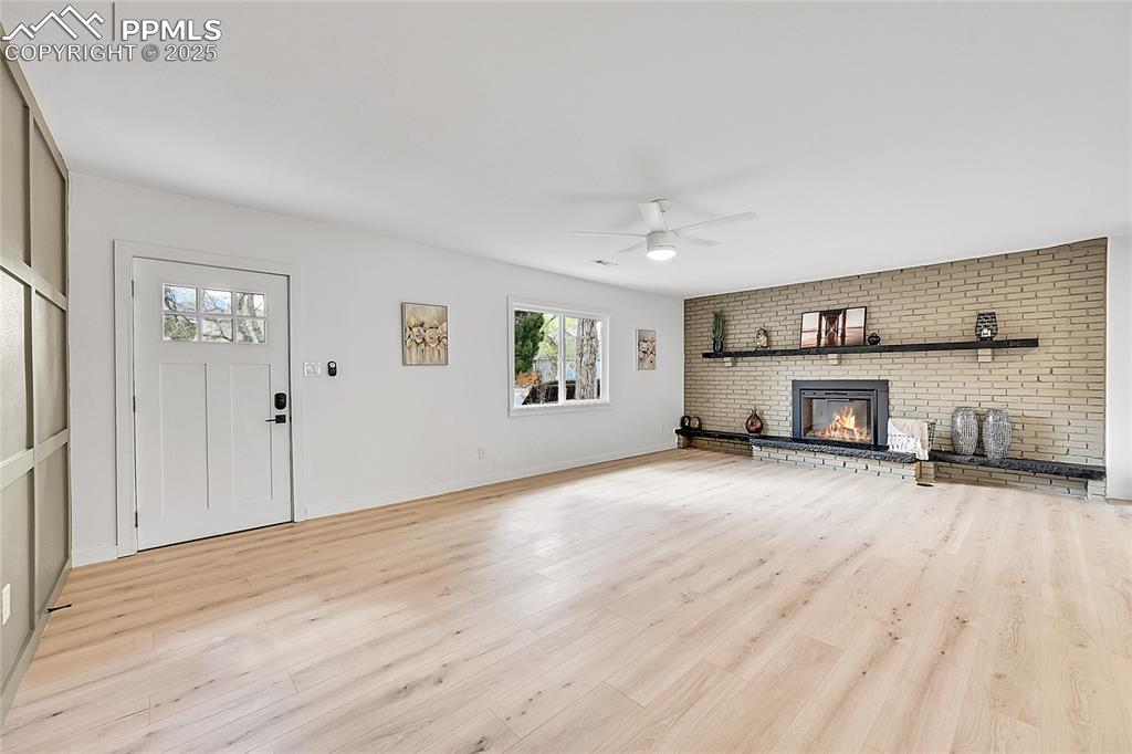 Image 4 of 28: Living room with a ceiling fan, a fireplace, and light wood finished floors