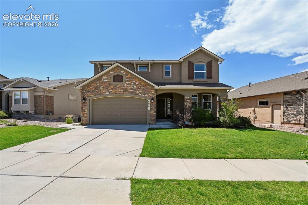 Caption: Two-story residence featuring a stone and stucco exterior, an attached garage, a covered front porch