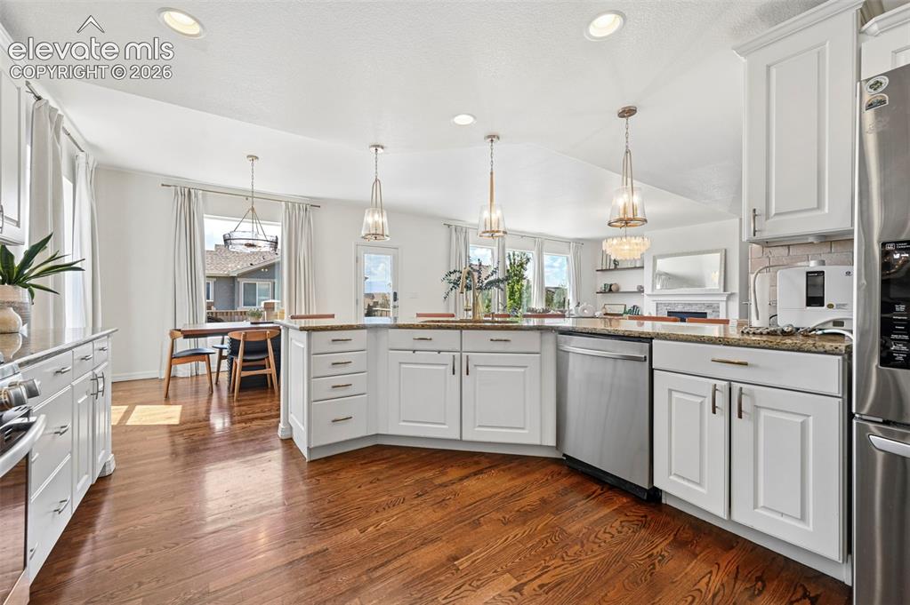 Image 11 of 50: Hardwood flooring throughout, white cabinetry with modern hardware, granite