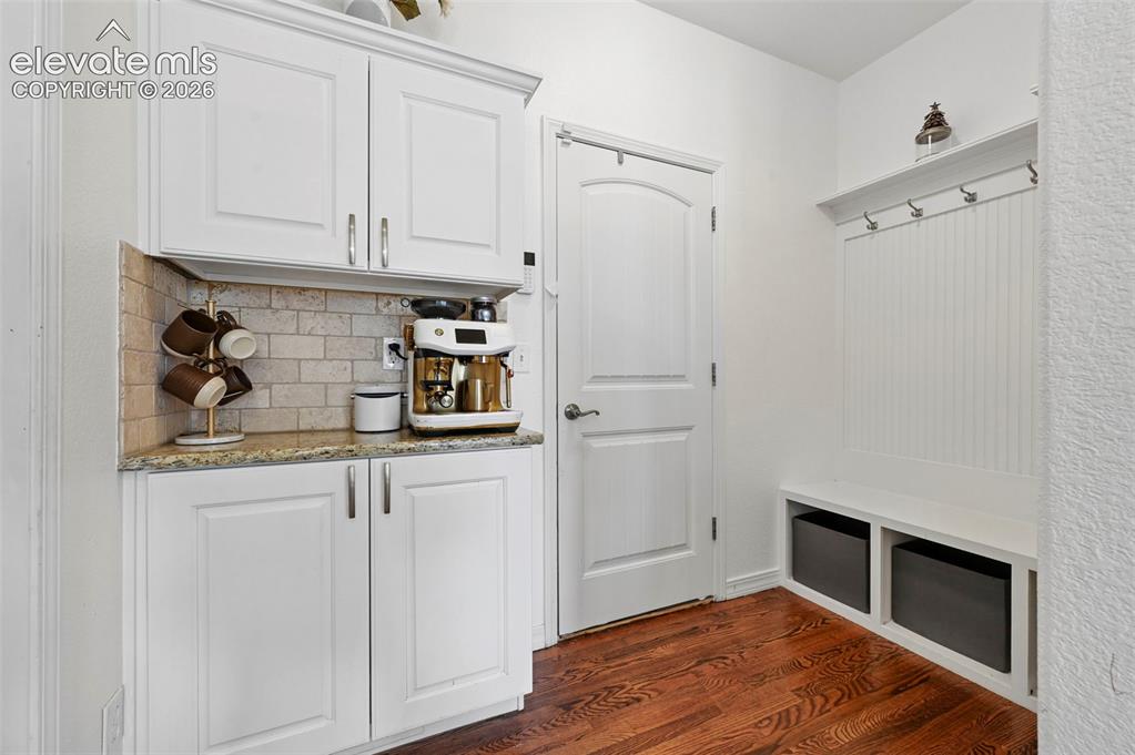 Image 12 of 50: White cabinetry with brushed nickel hardware, granite countertop, and tile 