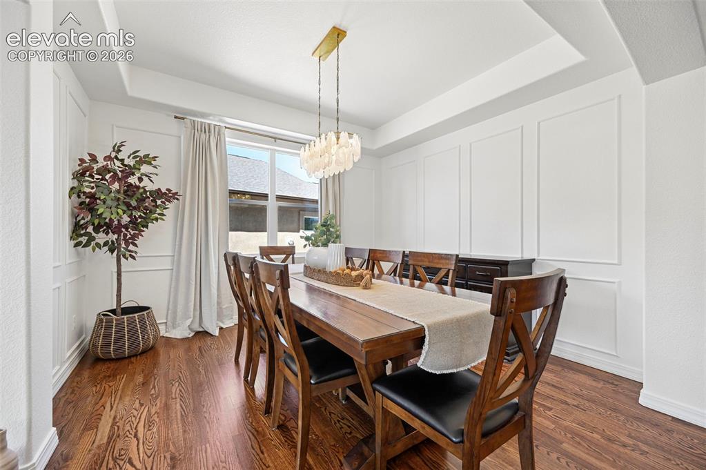 Image 15 of 50: Tray ceiling with recessed lighting, wood-finish flooring, and white wall p