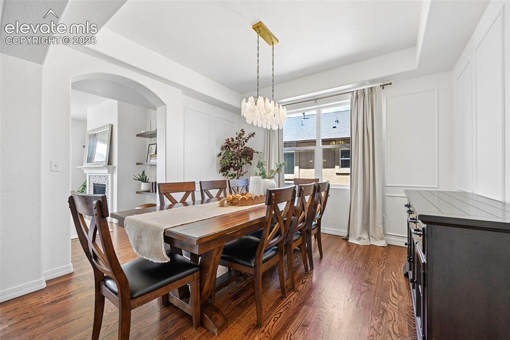 Image 16 of 50: Wood-finish flooring, tray ceiling, decorative wall molding, arched doorway