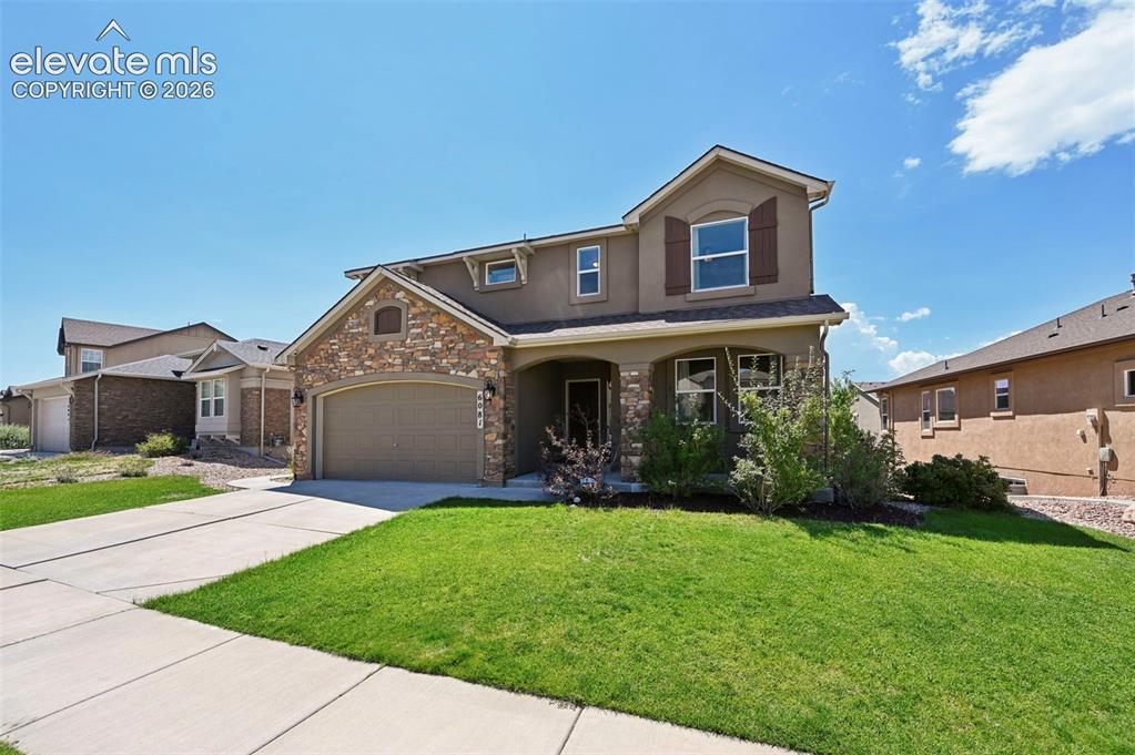 Image 2 of 50: Stone and stucco exterior with an attached garage, covered front entry, and