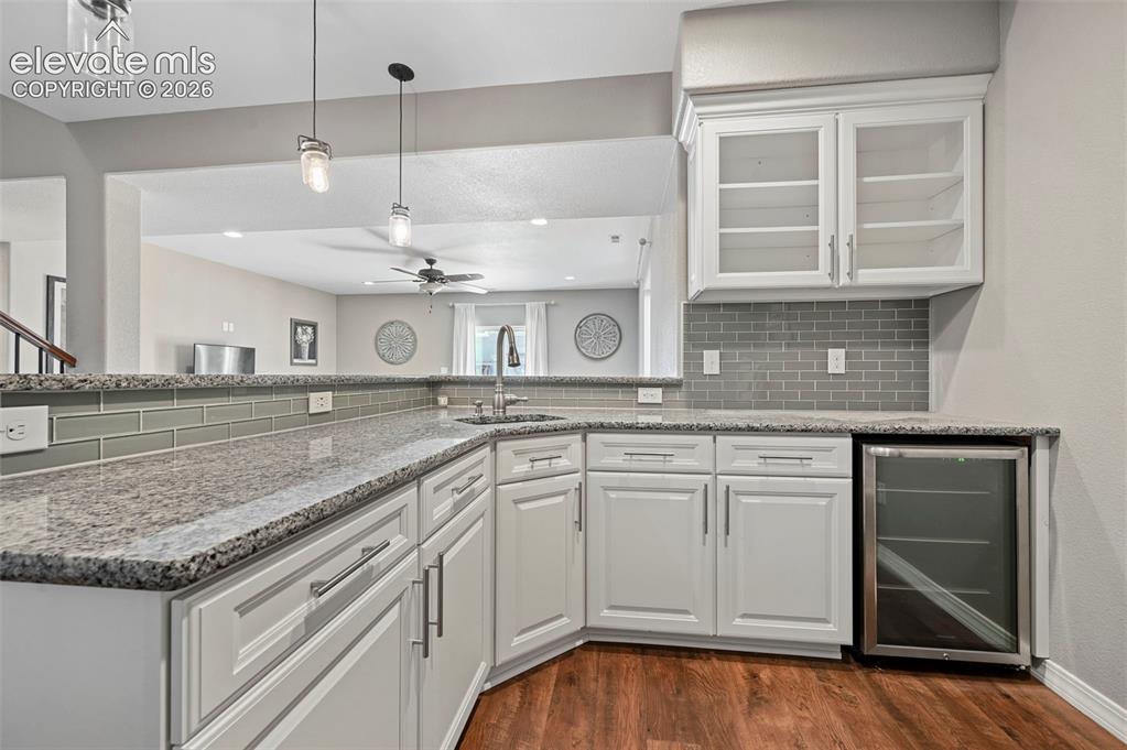 Image 26 of 50: Built-in beverage cooler, upper glass-front cabinetry, subway tile backspla