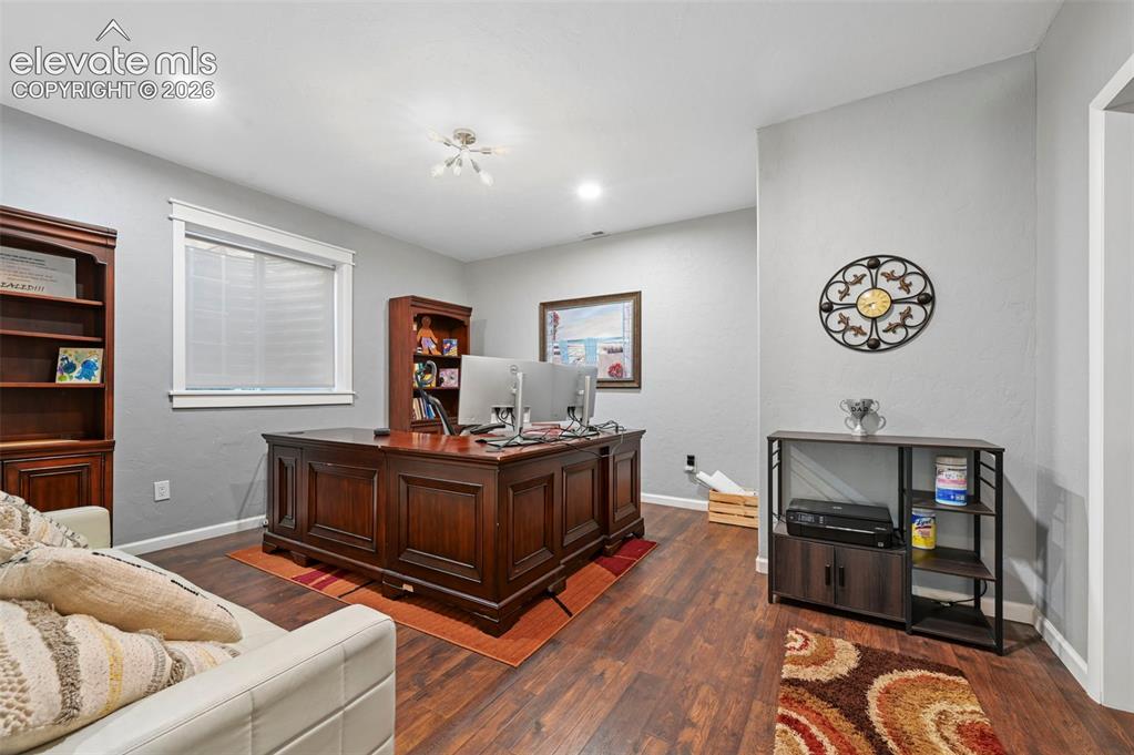 Image 28 of 50: Recessed lighting, wood-finish flooring, and a single window with blinds