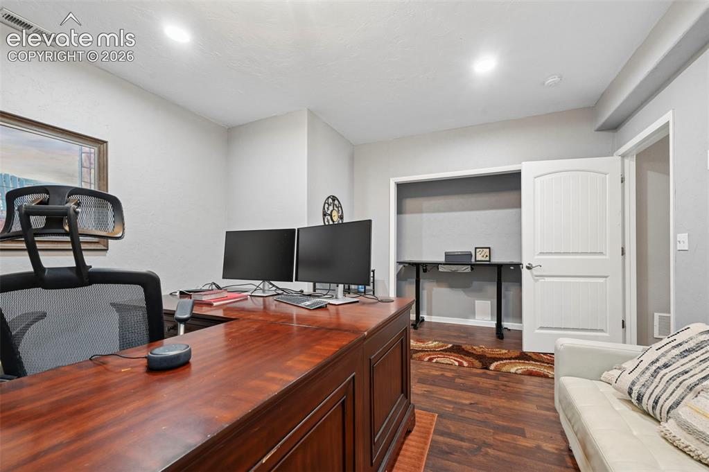 Image 29 of 50: Wood-finish flooring, recessed lighting, and a white paneled door