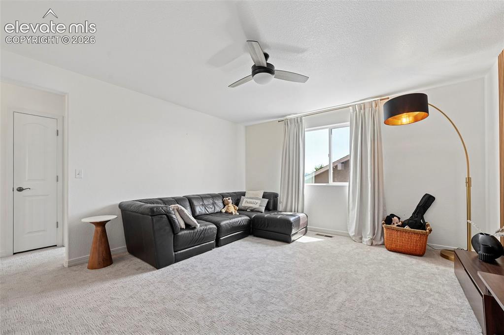 Image 33 of 50: Neutral-toned carpeting, white walls, and a ceiling fan with integrated lig