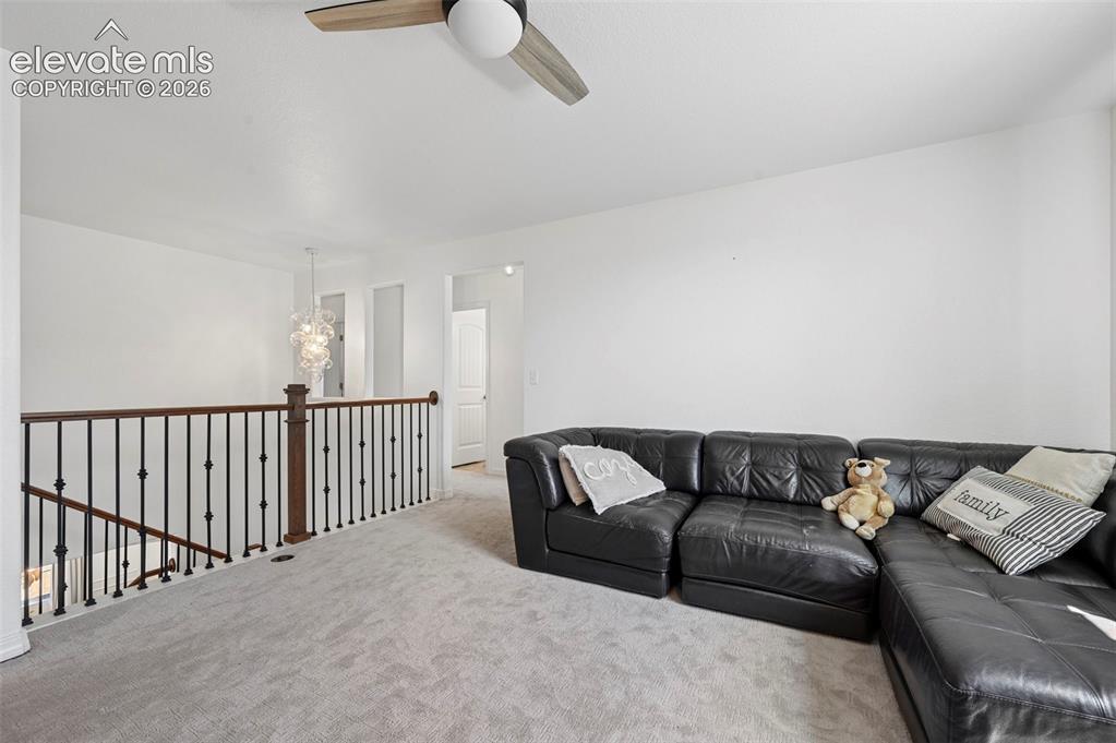 Image 34 of 50: Carpeted loft space featuring an open railing, overhead ceiling fan, and de