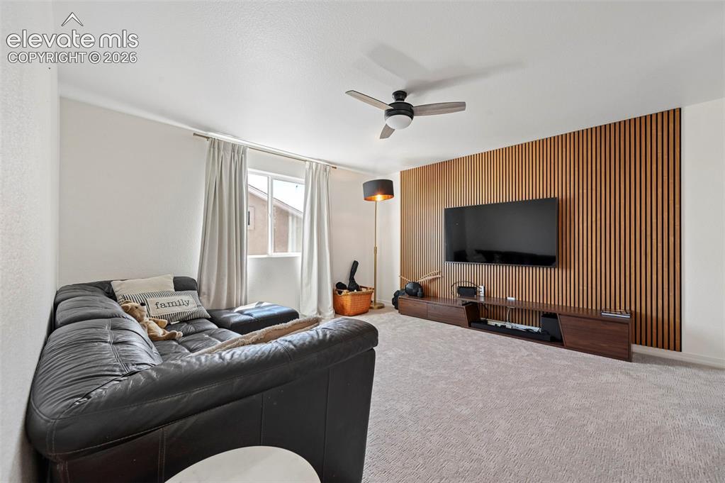 Image 35 of 50: Accent wall with vertical wood paneling, ceiling fan with integrated lighti