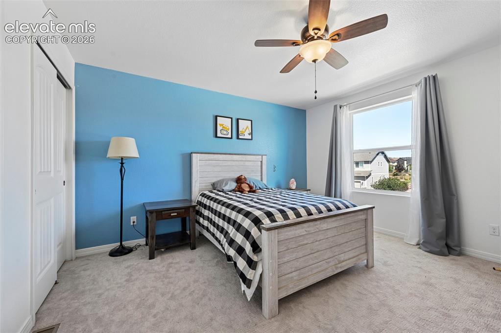 Image 39 of 50: Light-colored carpeting, a single window, and a ceiling fan with integrated