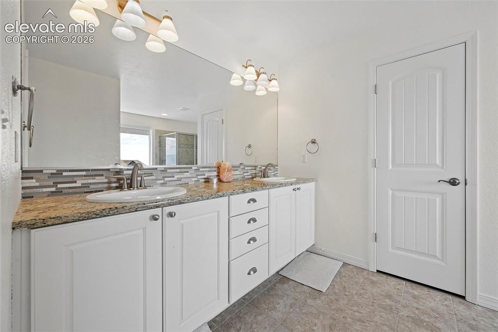 Image 47 of 50: Dual vanity with white cabinetry, granite-finish countertops, and under-mou