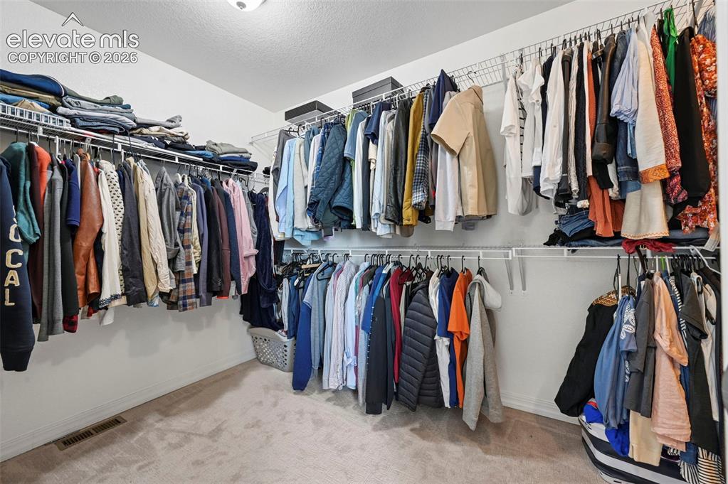 Image 49 of 50: Wall-mounted wire shelving system, multiple hanging rods, and light-colored