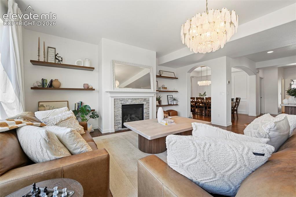 Image 6 of 50: Living room featuring a fireplace with stone surround, wood-finish flooring